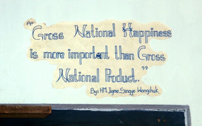 Slogan painted on a wall: "Gross National Happiness is more important than Gross National Product" by Jigme Singye Wangchuck, King of Bhutan